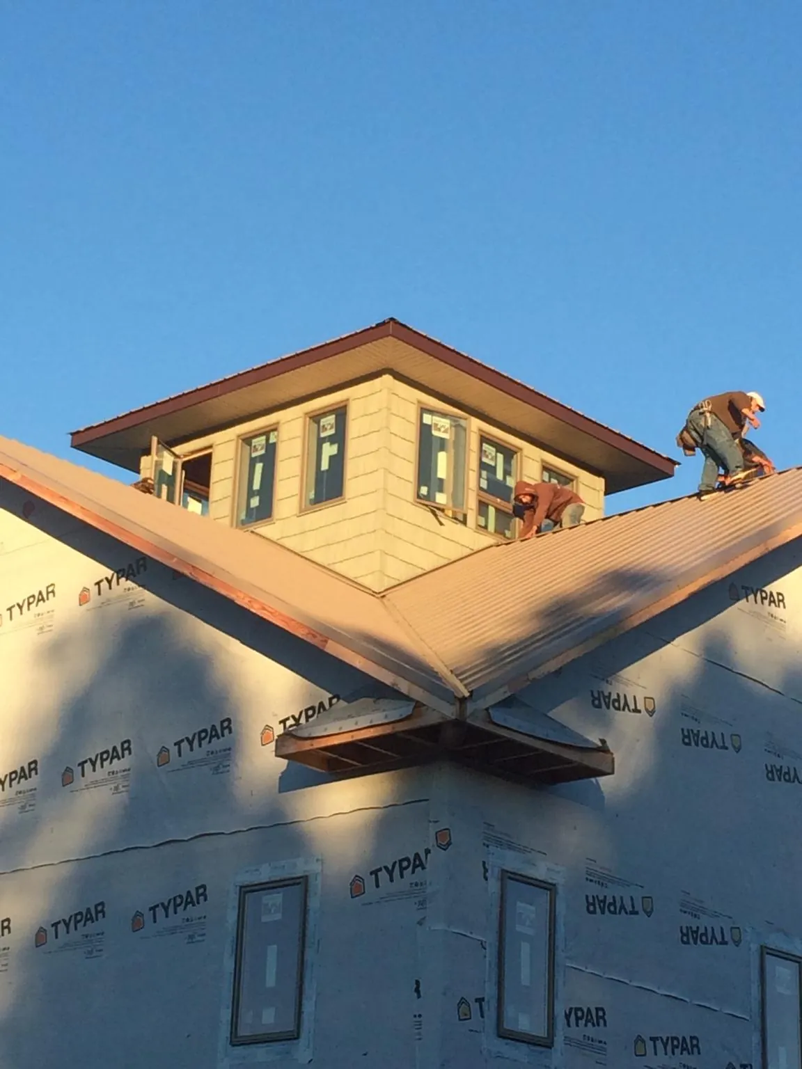 Roofers working around a rooftop cupola on a new metal roof at sunset — Roof Waterproofing in Dana by Roofing Brothers